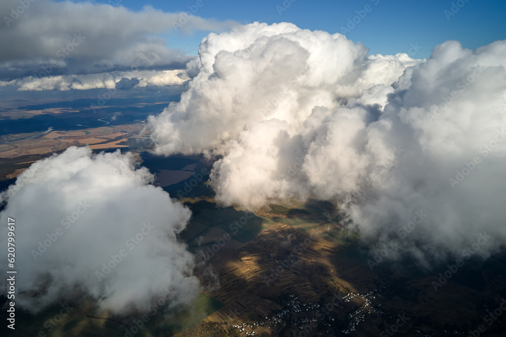 Aerial view at high altitude of earth covered with puffy cumulus clouds forming before rainstorm