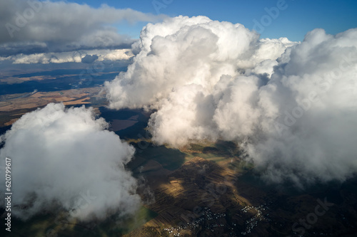 Aerial view at high altitude of earth covered with puffy cumulus clouds forming before rainstorm © bilanol