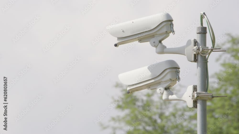 Rack focus toward white CCTV cameras mounted on metal post, close-up Rack focus toward white CCTV cameras mounted on metal post, close-up