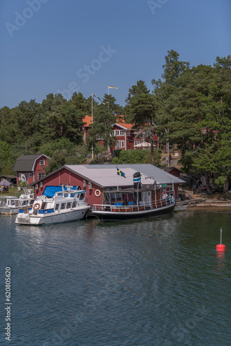 Island, skerries and islet, in the middle part of the archipelago. Bay with a boat shed and taxi boats and old steam boat on the island Möja, a sunny summer day in Stockholm