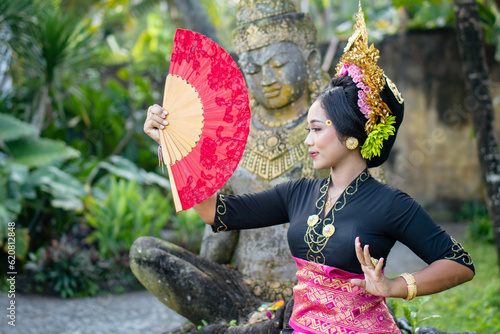 Woman poses in front of a Buddha statue in a costume and a crown in hair photo