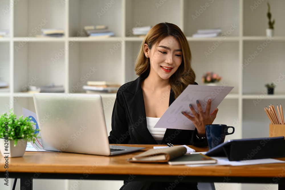Charming asian woman entrepreneur using laptop, working on investment and marketing projects at modern office Charming asian woman entrepreneur using laptop, working on investment and marketing projects at modern office