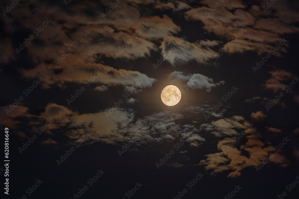 Dark night sky with full Moon and colored clouds. HDR photo taken through a telephoto lens Dark night sky with full Moon and colored clouds. HDR photo taken through a telephoto lens