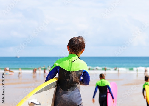 A child with a surfboard. Surfer school in summer, on a beach