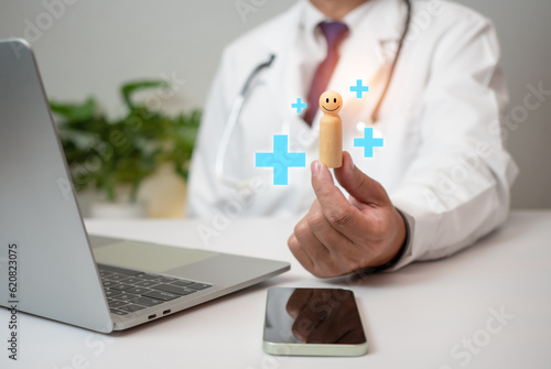 Doctor holding wood doll and plus sign at hospital office. Medical health care and medical services.