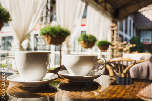 Cups of coffee and tea are on a glass table in the gazebo. Served for tea. table on the summer terrace of the cafe. morning ritual before work day. Rest between work and coffee break