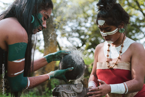 Mayan women with traditional garments performing smoke ritual with rubber ball photo