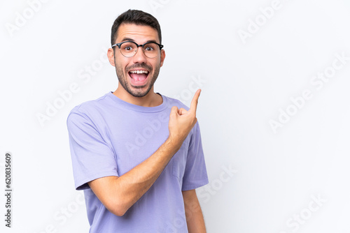 Young caucasian man isolated on white background surprised and pointing side