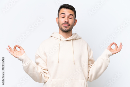 Young caucasian man isolated on white background in zen pose