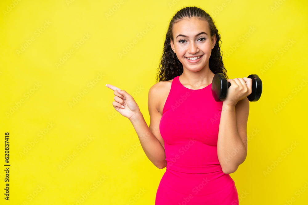 Young sport woman making weightlifting isolated on yellow background pointing finger to the side Young sport woman making weightlifting isolated on yellow background pointing finger to the side