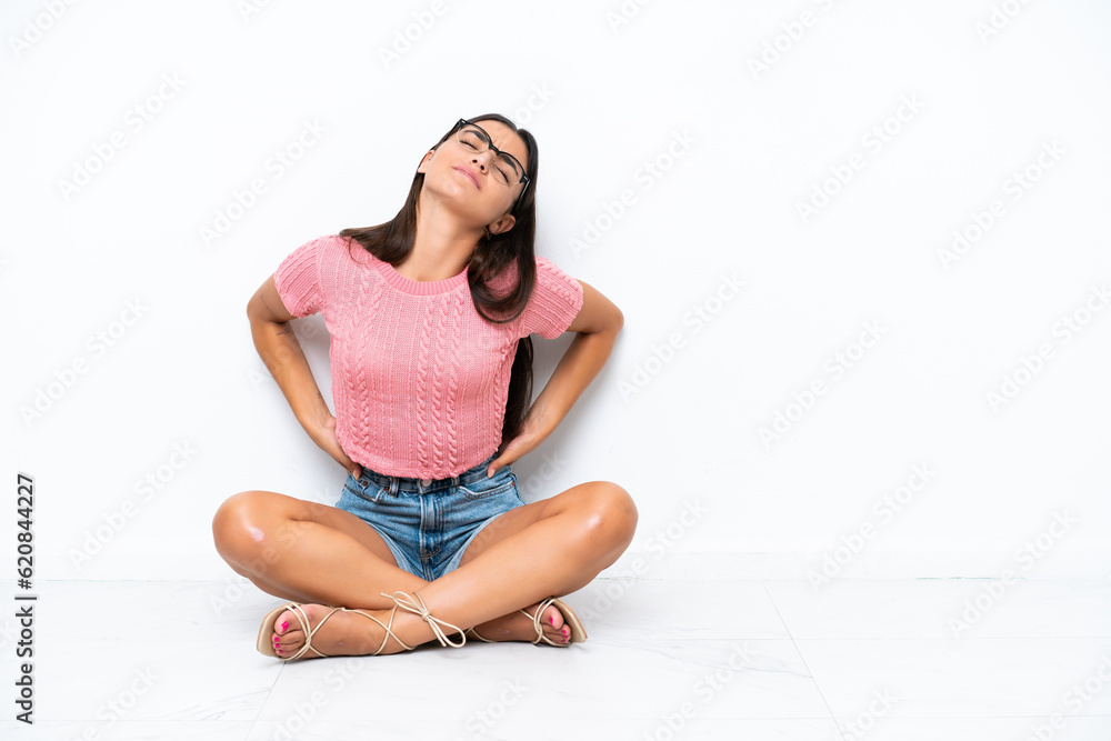 Young caucasian woman sitting on the floor isolated on white background suffering from backache for having made an effort Young caucasian woman sitting on the floor isolated on white background suffering from backache for having made an effort