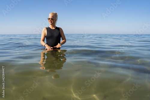 Tableau sur toile A girl in a calypso bathes in the cold Baltic Sea on a summer day