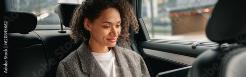 Cheerful businesswoman accountant working on laptop sitting car backseat on the way to office photo