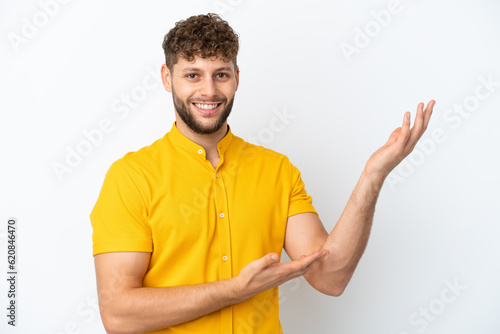 Young handsome caucasian man isolated on white background extending hands to the side for inviting to come