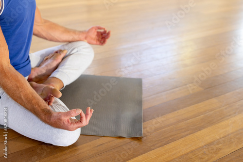 Lowsection of caucasian man practicing yoga meditation on mat in studio photo