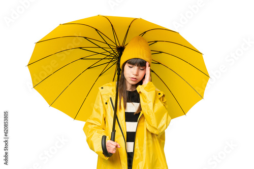 Little girl with rainproof coat and umbrella over isolated chroma key background with headache