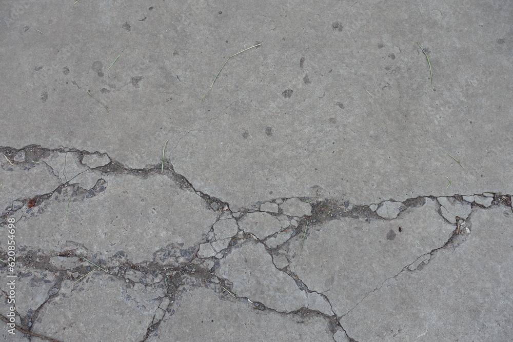 Fototapeta premium Worn dry light grey concrete slab with numerous cracks