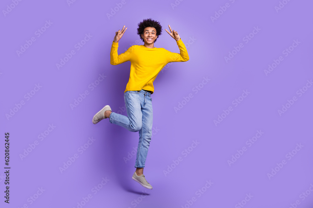 Full body photo of jump young man have fun show double v-sign symbol hello greetings wear jeans shirt isolated on purple color background