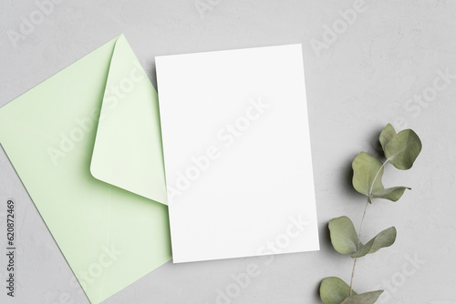 Blank wedding invitation card mockup with paper envelope and dry eucalyptus twig decor