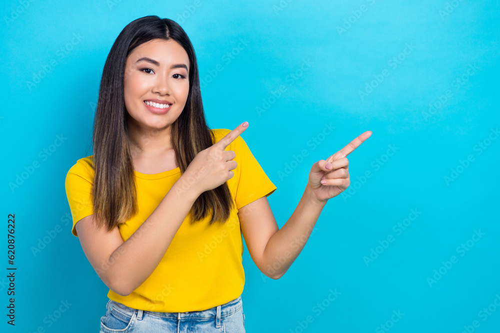 Portrait of nice asian beauty girl show novelty empty copy space direct fingers wear yellow t-shirt isolated blue teal color background Portrait of nice asian beauty girl show novelty empty copy space direct fingers wear yellow t-shirt isolated blue teal color background