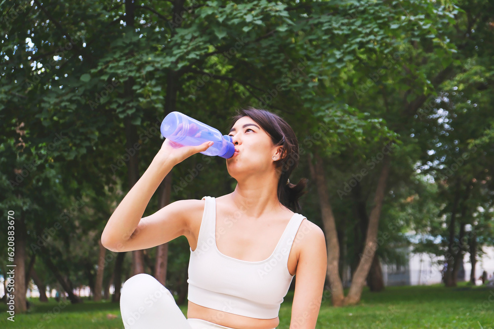 Asian sportif girl is drinking water from bottle in park outdoor. Asian sportif girl is drinking water from bottle in park outdoor.