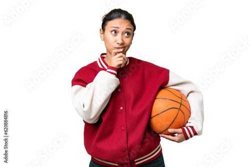 Young Uruguayan woman playing basketball over isolated wall  over isolated chroma key background having doubts