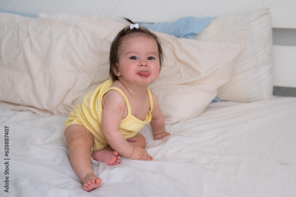 mixed ethnicity Asian Caucasian baby girl sitting on bed sweet and
