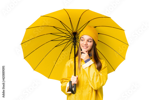 Teenager girl with rainproof coat and umbrella over isolated chroma key background looking to the side and smiling
