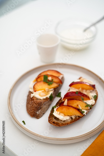Cottage cheese and peach slices on a slice of white bread. White background and yellow towel. Breakfast or brunch in a work day or in a sleepy day