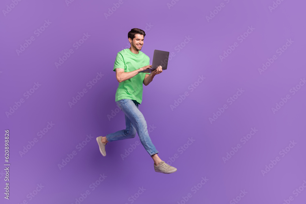 Full body cadre of jumping professional it specialist program developer running deadlines use laptop isolated on violet color background
