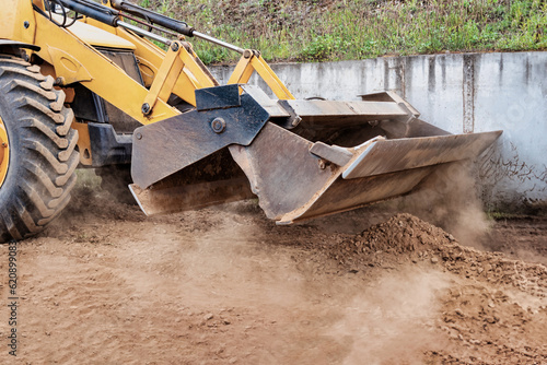 Powerful wheel loader or bulldozer at the construction site. Loader transports sand in a storage bucket. Powerful modern equipment for earthworks and bulk handling.