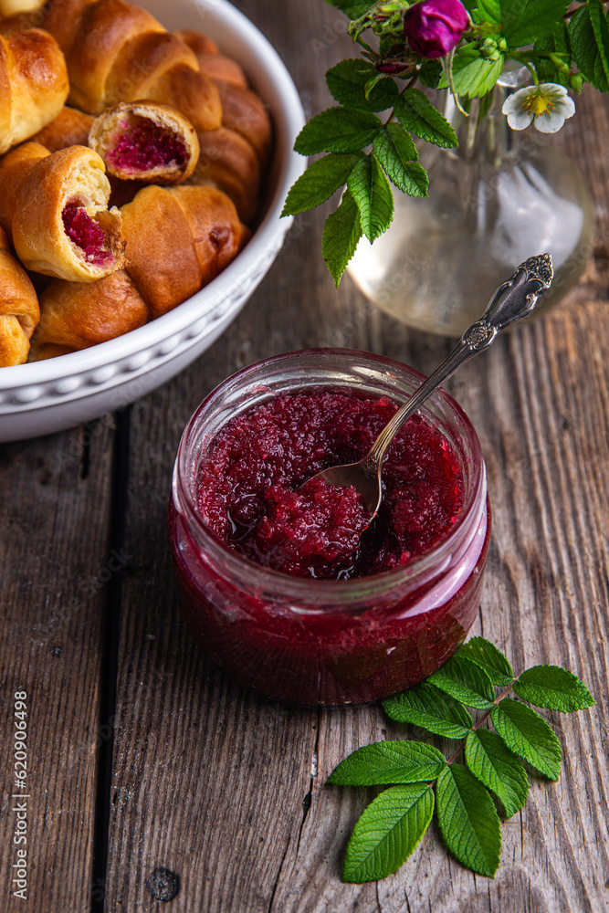 Glass jar with homemade edible rose jam and crescents with rose jam on old wooden table. Glass jar with homemade edible rose jam and crescents with rose jam on old wooden table.