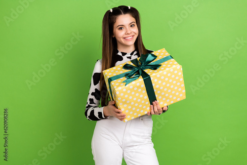 Photo of shiny cheerful lady wear cow skin shirt holding gift box isolated green color background © deagreez