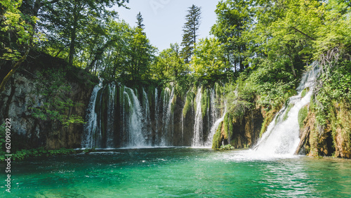 Enormous waterfall with green tones and blue water in Plitvice Lakes National Park 