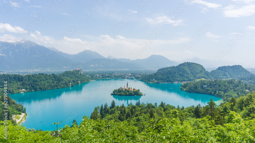 Beautiful panorama of the beautiful Bled lake on a sunny day with blue tones on the water and green vegetation surrounding the lake