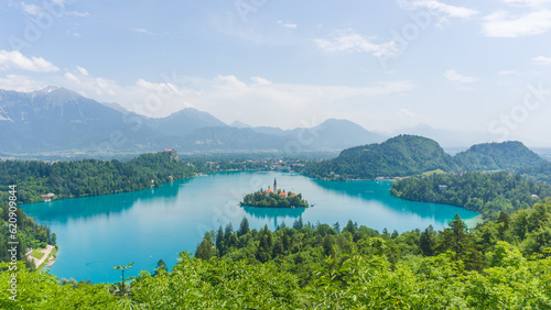 Beautiful panorama of the beautiful Bled lake on a sunny day with blue tones on the water and green vegetation surrounding the lake