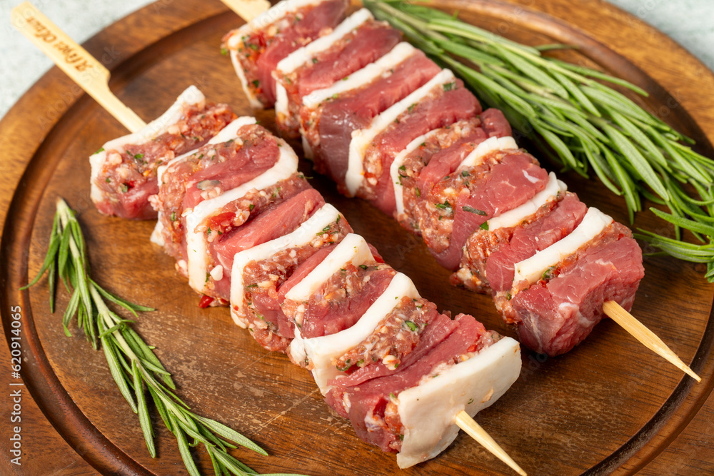 Beef skewer. Shish kebab prepared with raw ribeye and minced meat on a gray background Beef skewer. Shish kebab prepared with raw ribeye and minced meat on a gray background