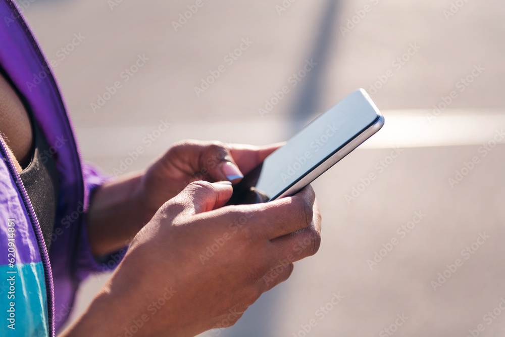 Close up photo with selective focus on the hands of a sportive african american woman using a mobile phone, concept of technology of communication and sportive lifestyle