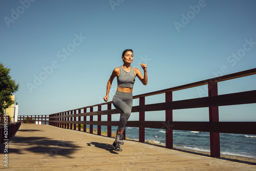 beautiful brunette girl in gray leggings runs on the seashore © sutulastock