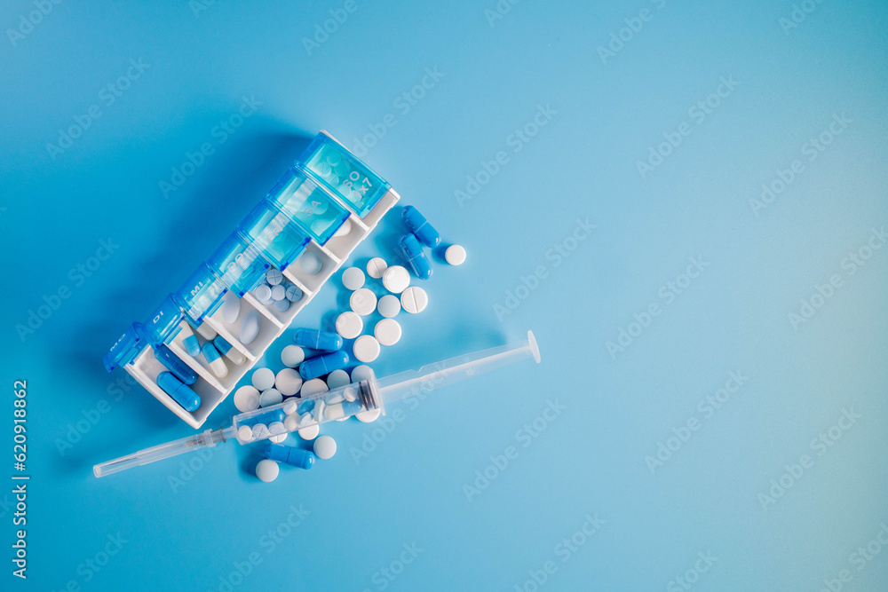 Top view of weekly pill box organizer, portable travel prescription or medication pill case on blue background. Healthcare and medical concept.