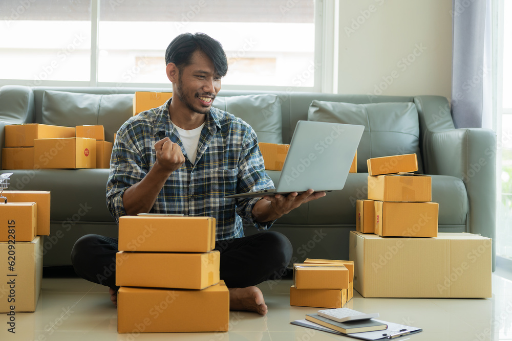 Young Asian business owner excited to receive orders from customers and pack items for customers. E-commerce, online shopping, SME business concept. Young Asian business owner excited to receive orders from customers and pack items for customers. E-commerce, online shopping, SME business concept.