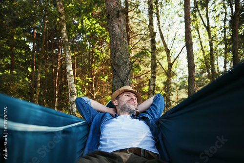 Adult man chilling in hammock in a forst during summer vacation