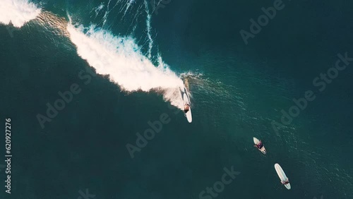 Woman surfs the wave on Batu Bolong surfing spot in Bali, Indonesia. Aerial top down view of the female surfer riding the wave