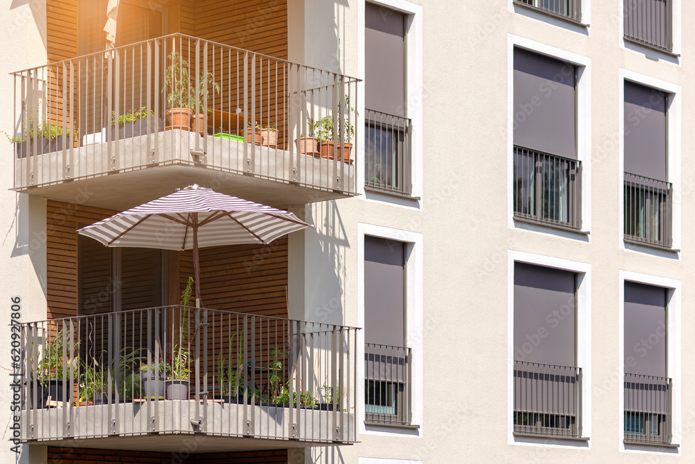 Fototapeta premium Sun Protection of Modern Apartment Bilding with External Roller Blinds or Shutters Outside, Sun Umbrella on Solar Balcony.