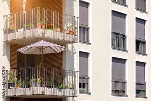 Sun Protection of Modern Apartment Bilding with External Roller Blinds or Shutters Outside, Sun Umbrella on Solar Balcony.