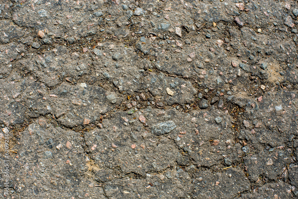 A network of black cracks on the asphalt surface. Road texture with weathered surface, showcasing the effects of time and wear A network of black cracks on the asphalt surface. Road texture with weathered surface, showcasing the effects of time and wear