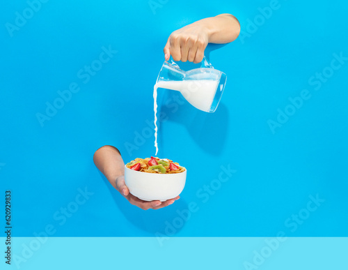 a hand pours milk from a jug into a bowl