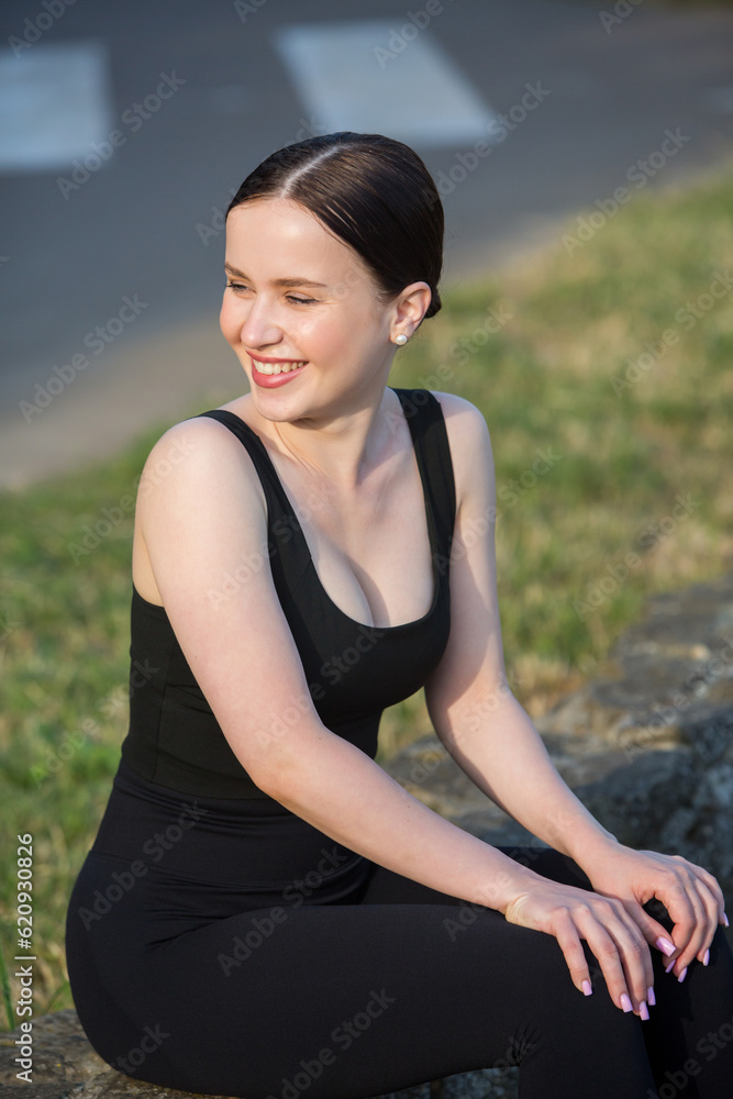 Portrait of smiling young woman in black sportswear exercising outdoors. Fitness and healthy lifestyle concept. Portrait of smiling young woman in black sportswear exercising outdoors. Fitness and healthy lifestyle concept.