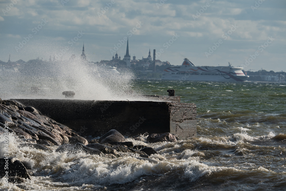 Storm, Wave breaks on a pier on a summer day, the action takes place in Tallinn, a cruise ship is in the background.