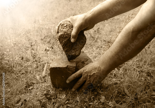 Photos Hands of primitive man with stone